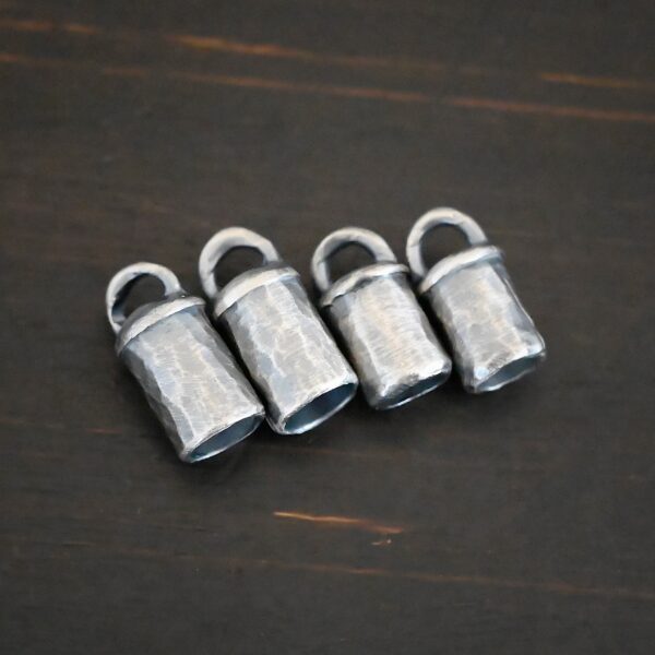 Handmade silver oxidized end caps on dark background