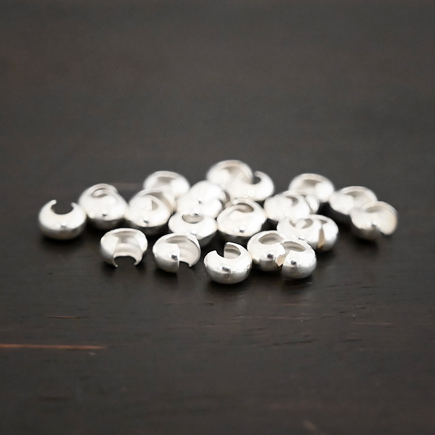 Silver shiny crimp covers shown on dark background