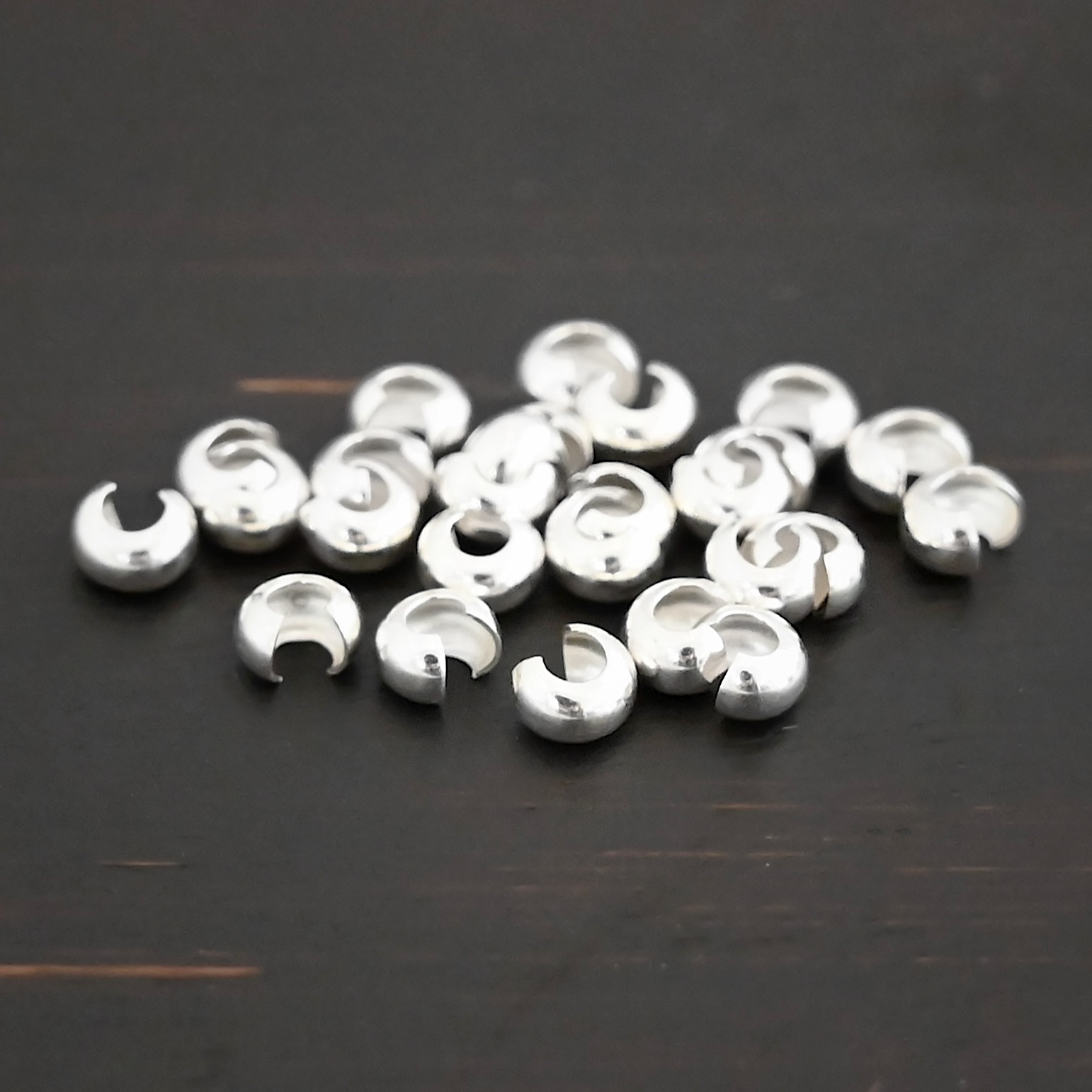 Silver shiny crimp covers shown on dark background