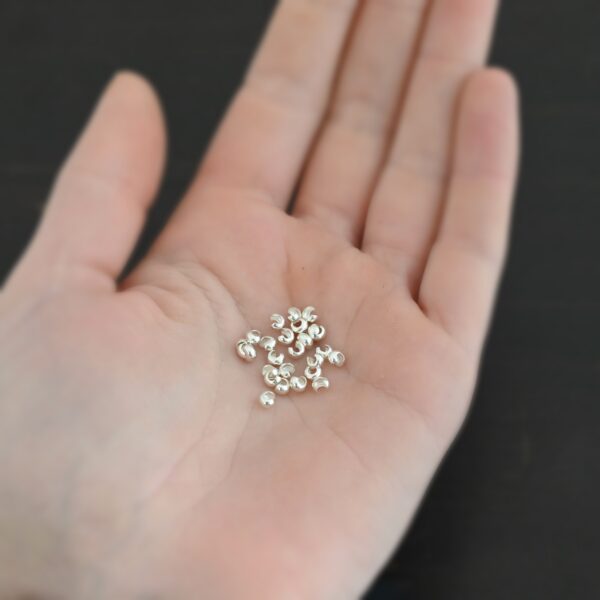 Silver shiny 3mm crimp covers shown in hand