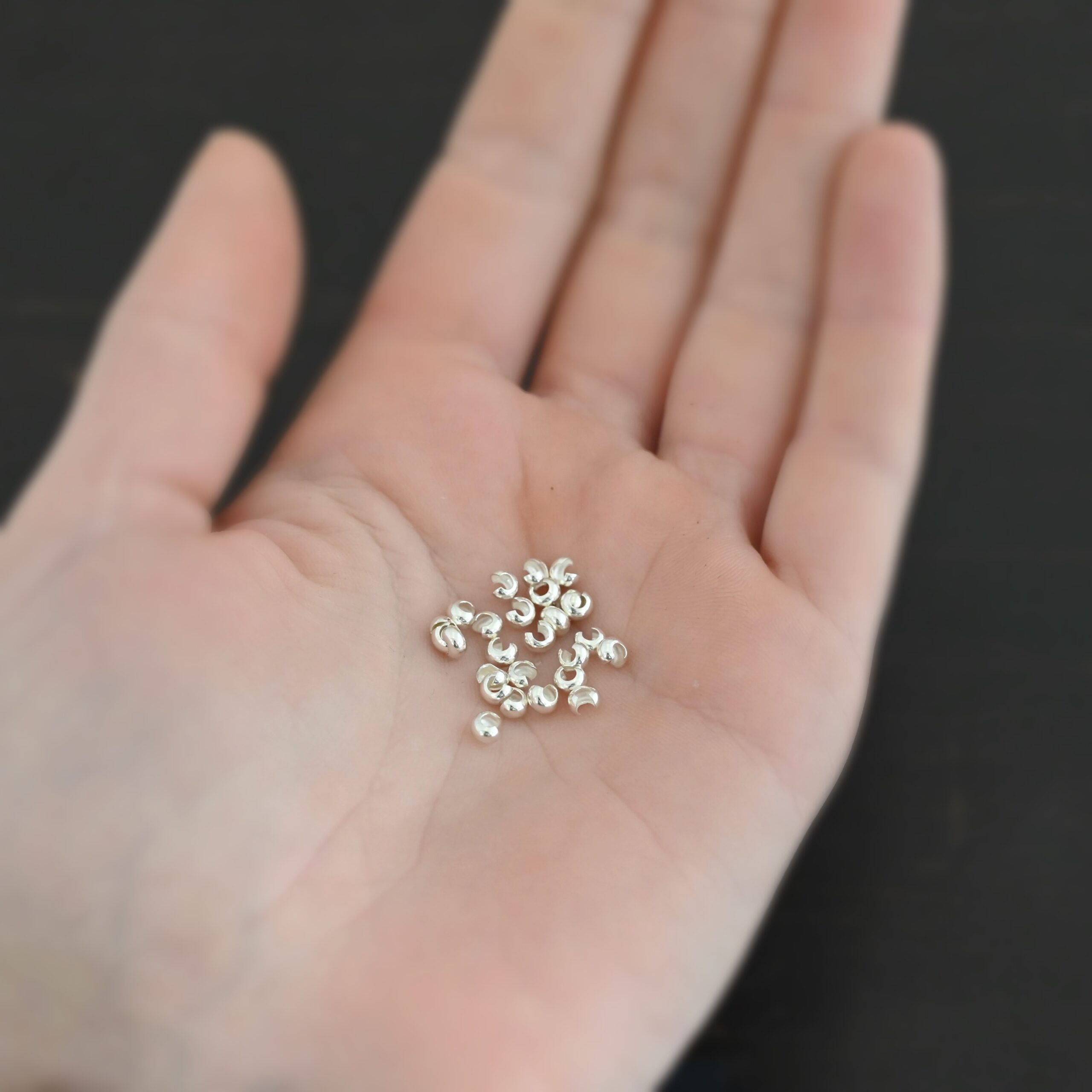 Silver shiny 3mm crimp covers shown in hand