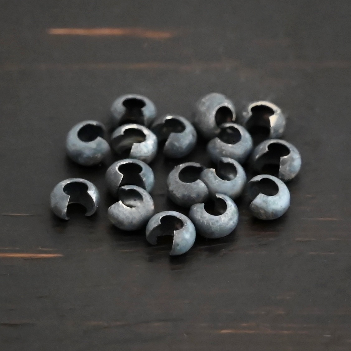 Silver oxidized crimp covers shown on dark background