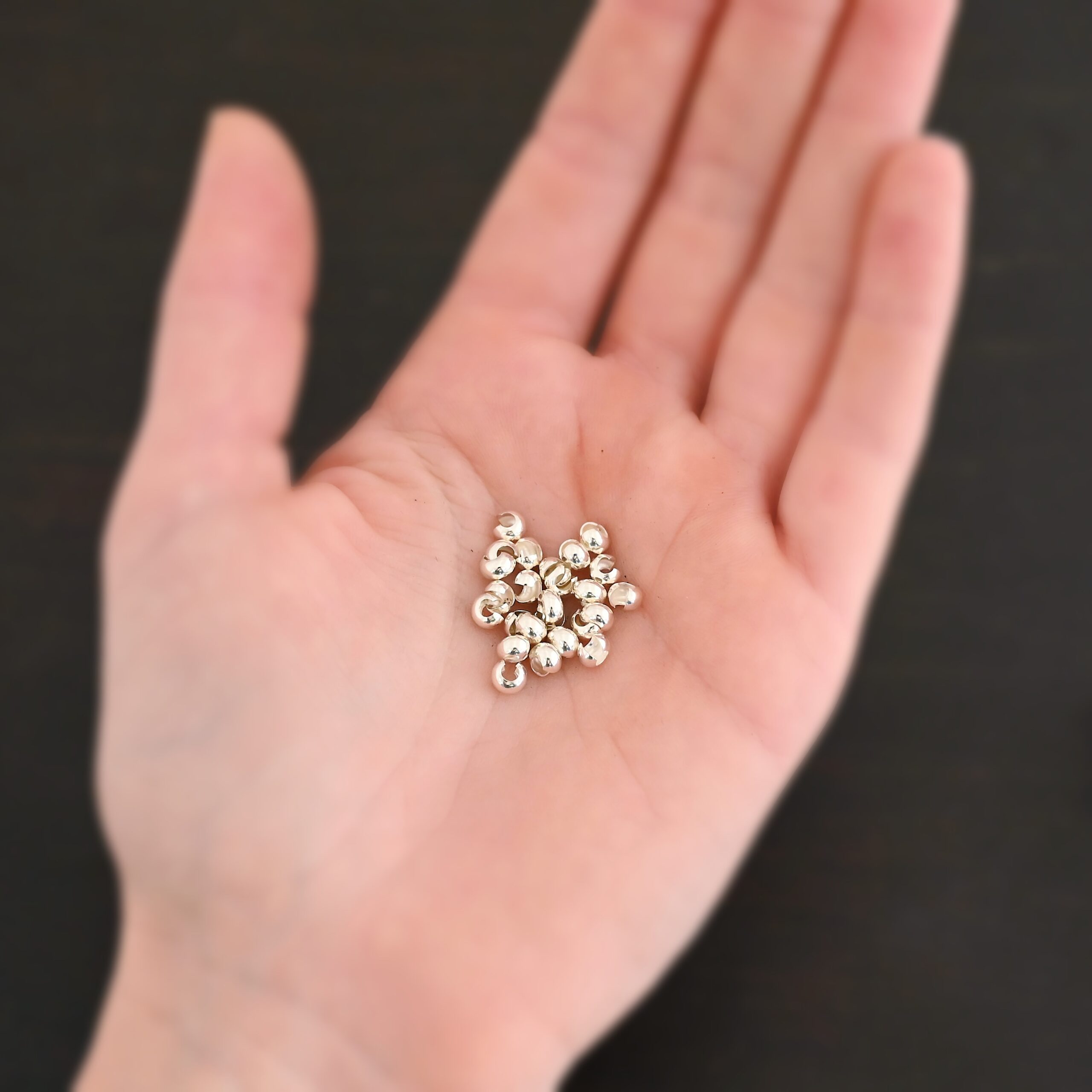 Silver shiny 4mm crimp covers shown in hand