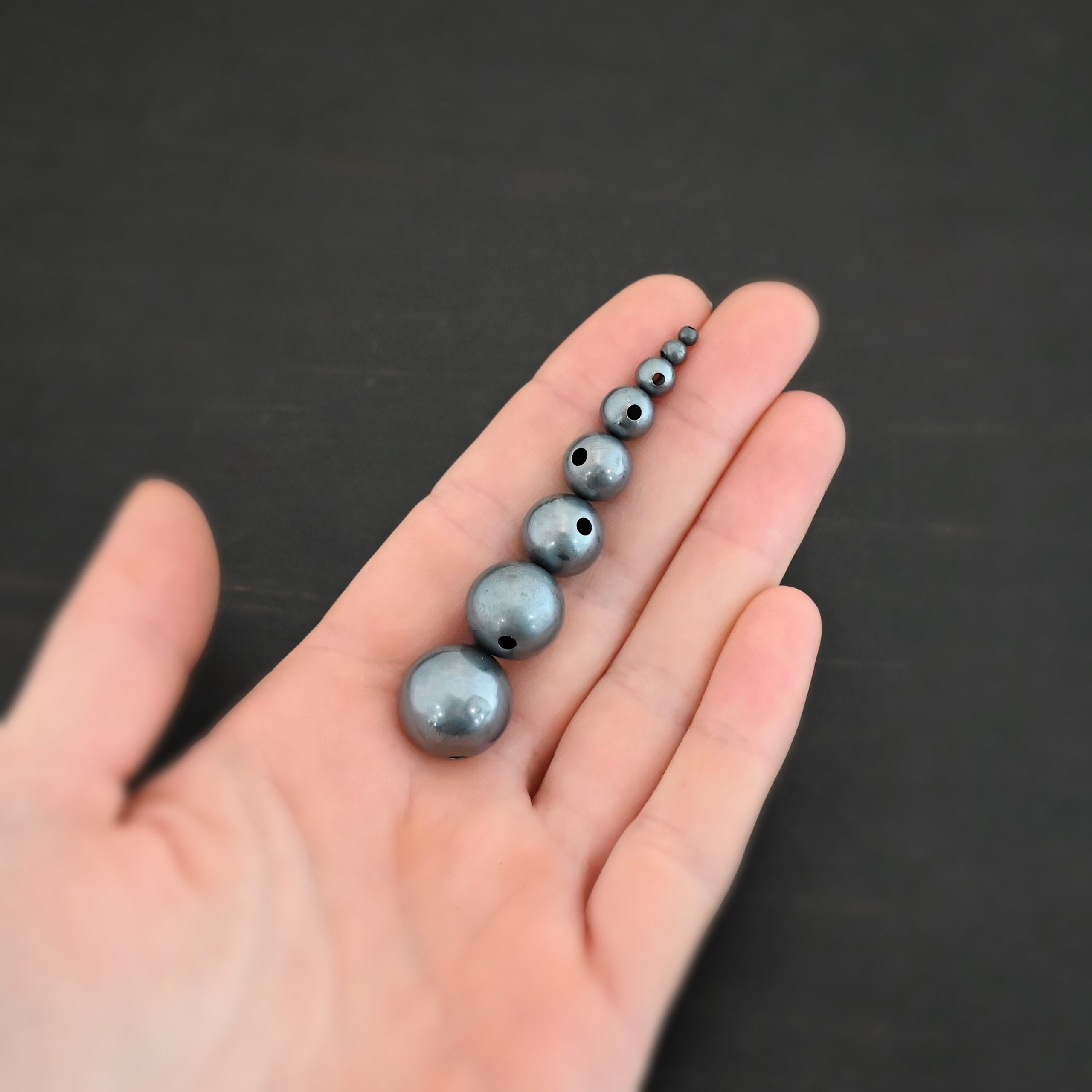 Silver oxidized hollow beads shown in hand