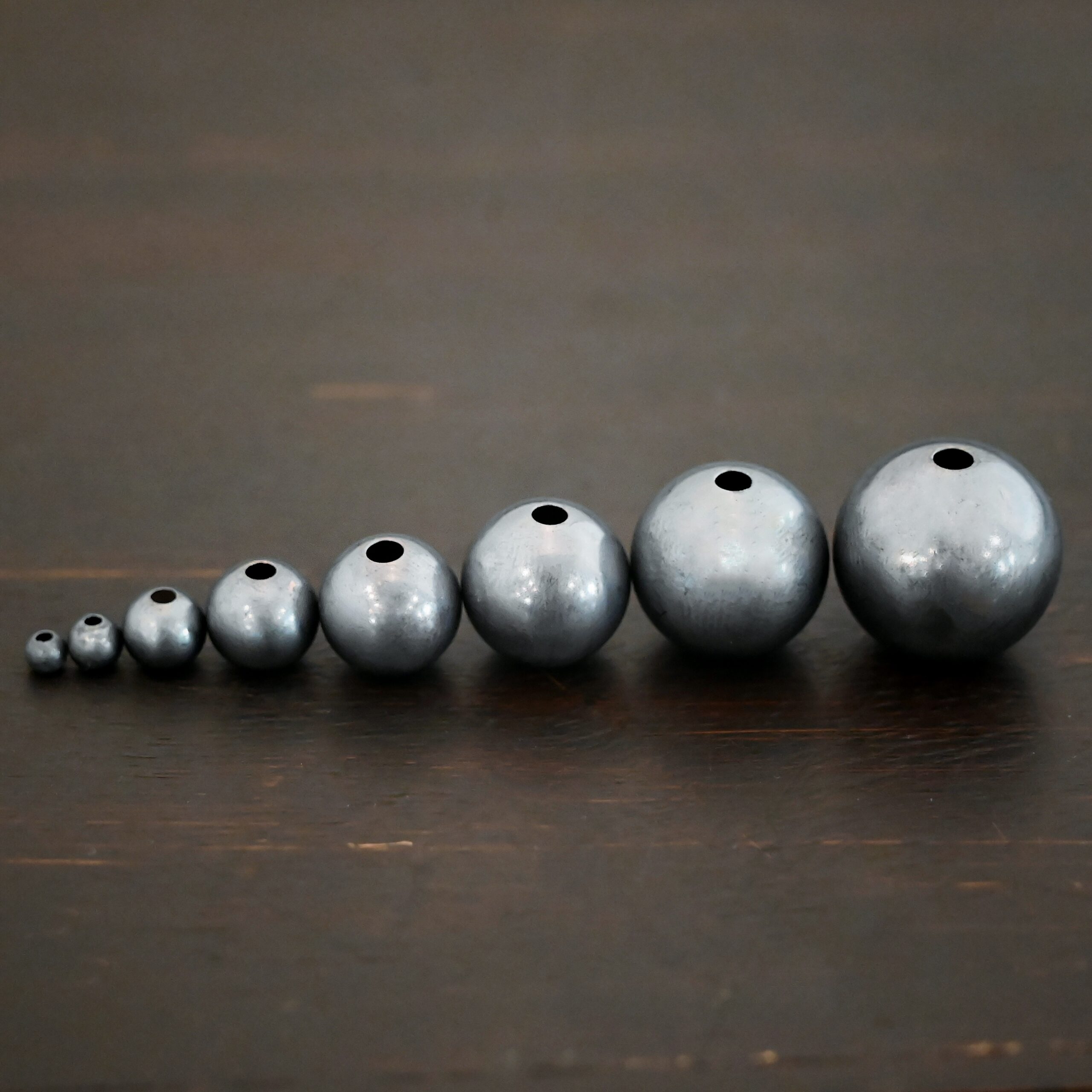 Silver oxidized hollow beads shown on dark background