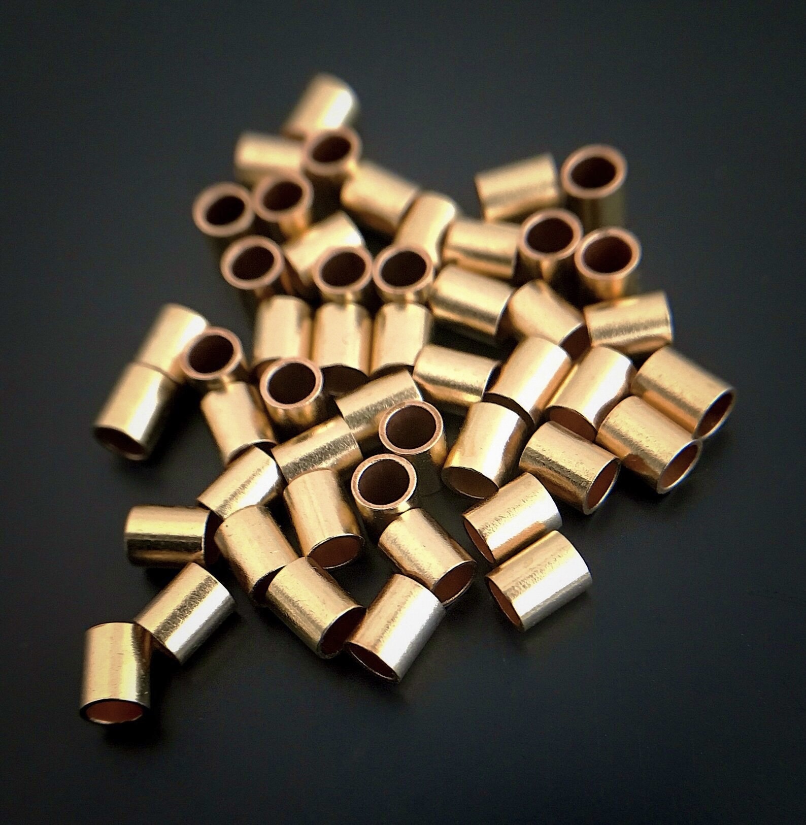 Gold Filled Tube Crimps shown on dark background
