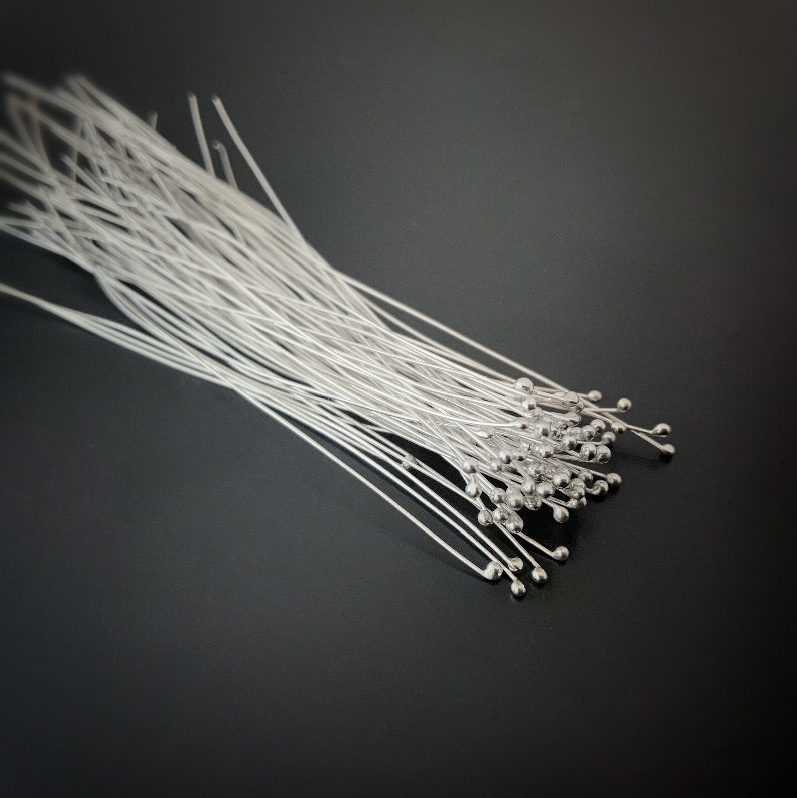 Smaller Ball Headpins Small Shiny Silver Ball Headpins shown on dark background