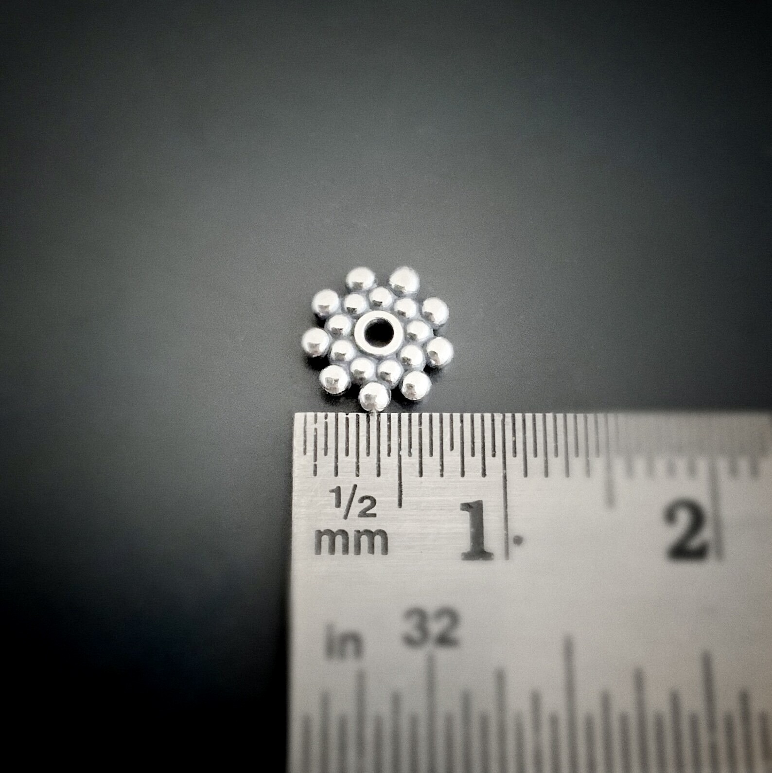 Silver 7mm daisy spacer shown by ruler