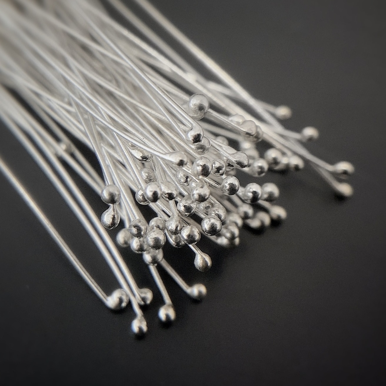 Smaller Ball Headpins Small Shiny Silver Ball Headpins shown on dark background