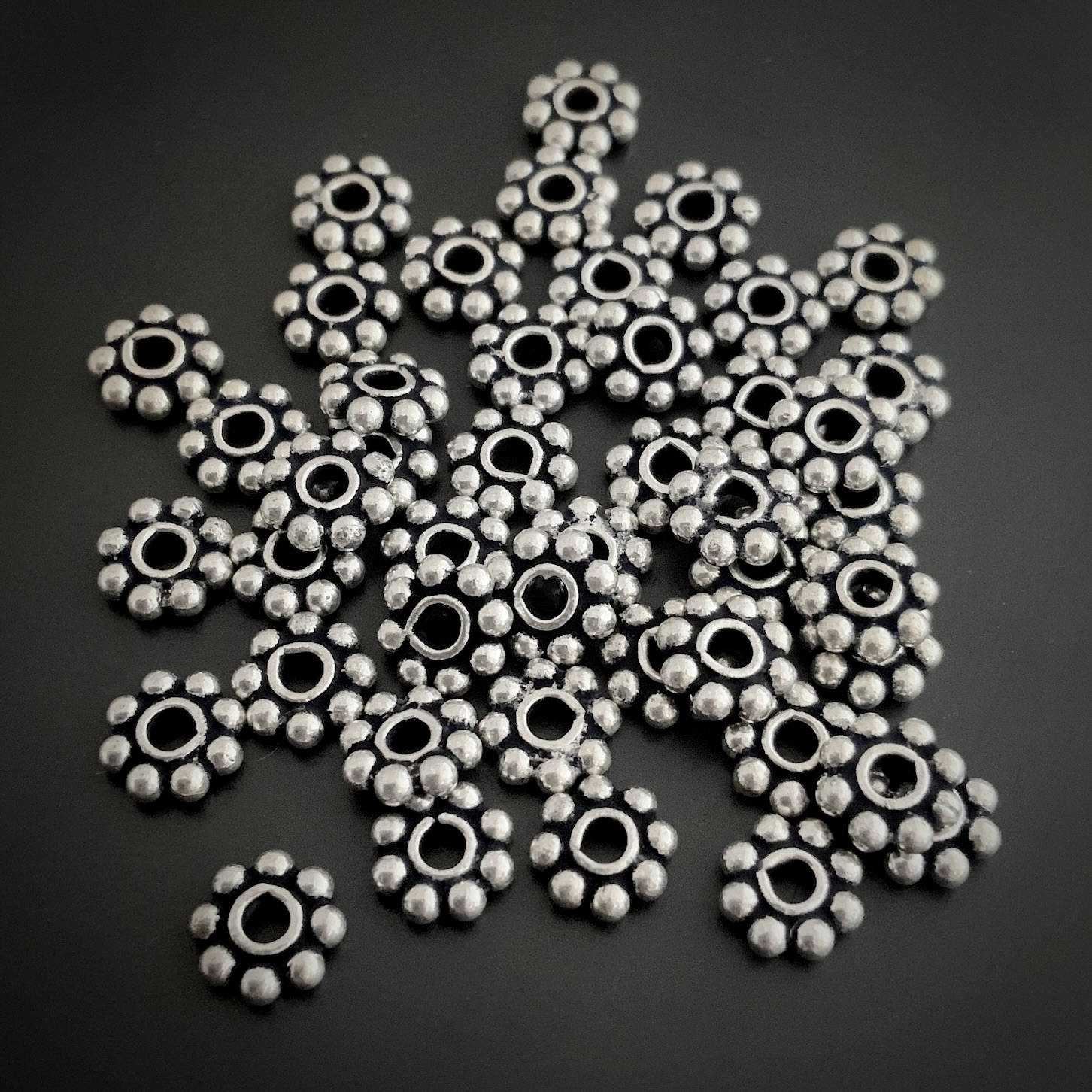 Silver daisy spacer shown on dark background