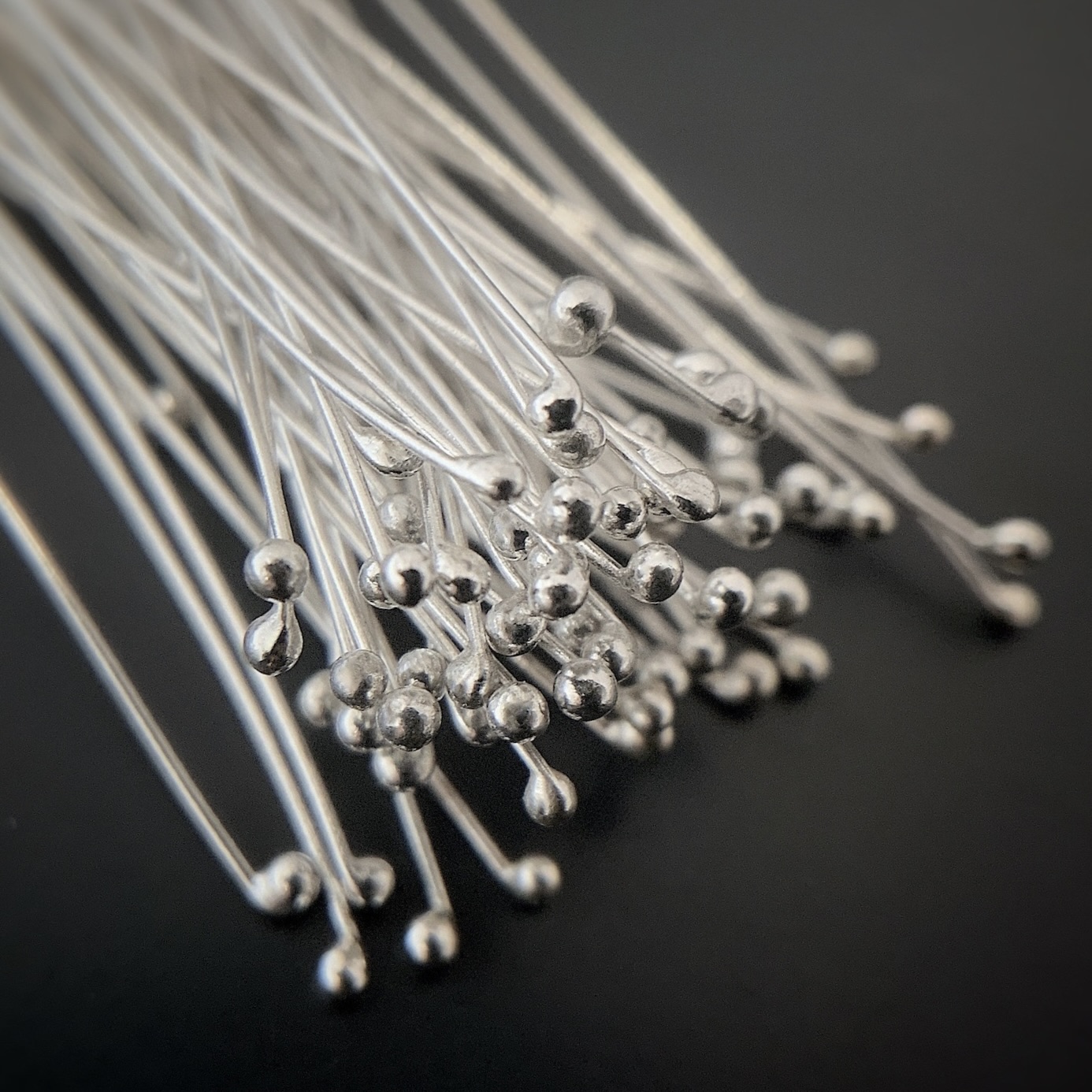 Smaller Ball Headpins Small Shiny Silver Ball Headpins shown on dark background
