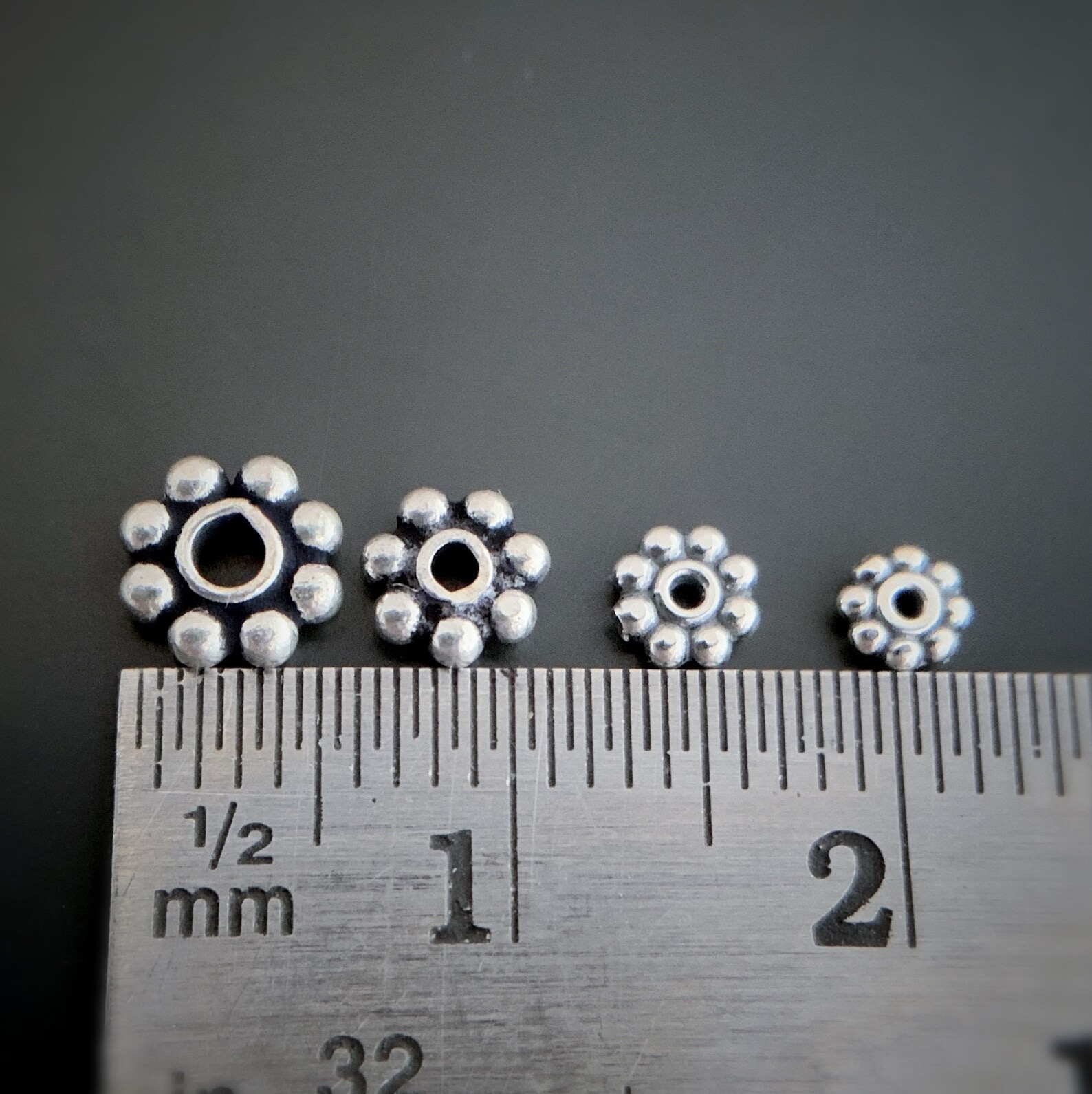 Silver daisy spacer shown by ruler