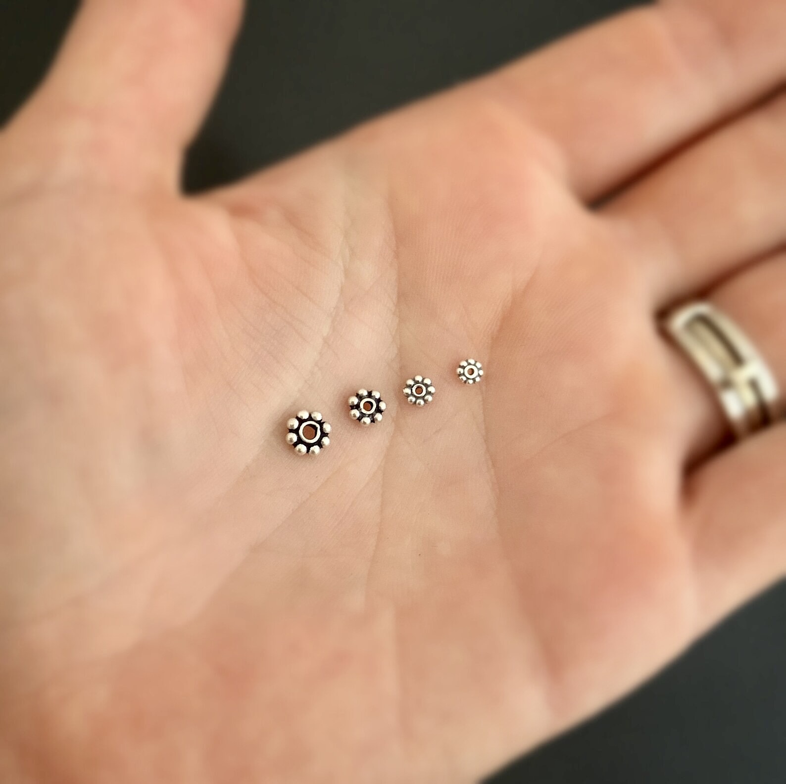 Silver daisy spacer shown in hand