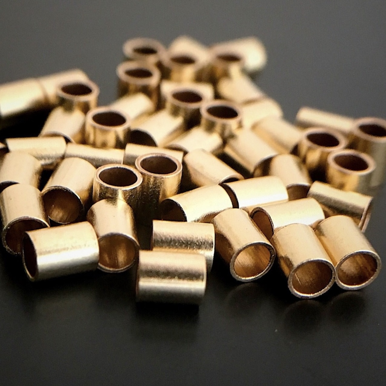 Gold Filled Tube Crimps shown on dark background