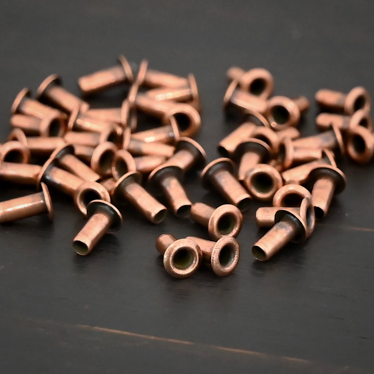 3/32x1/5 Copper plated eyelets shown on dark background