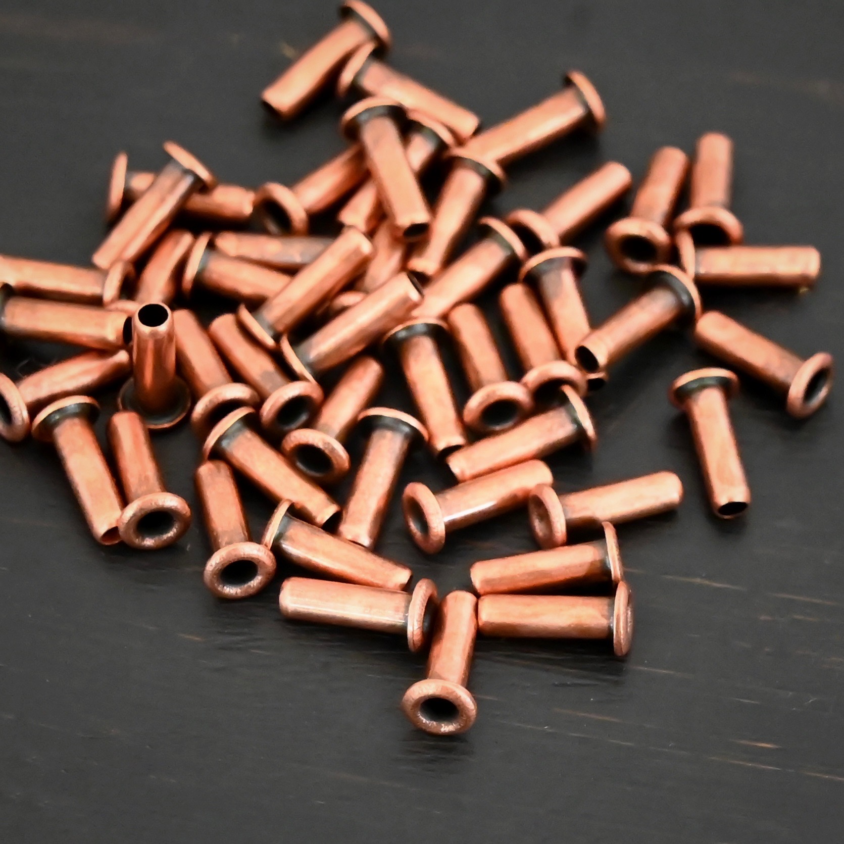 3/32x1/4 plated copper eyelets shown on dark background