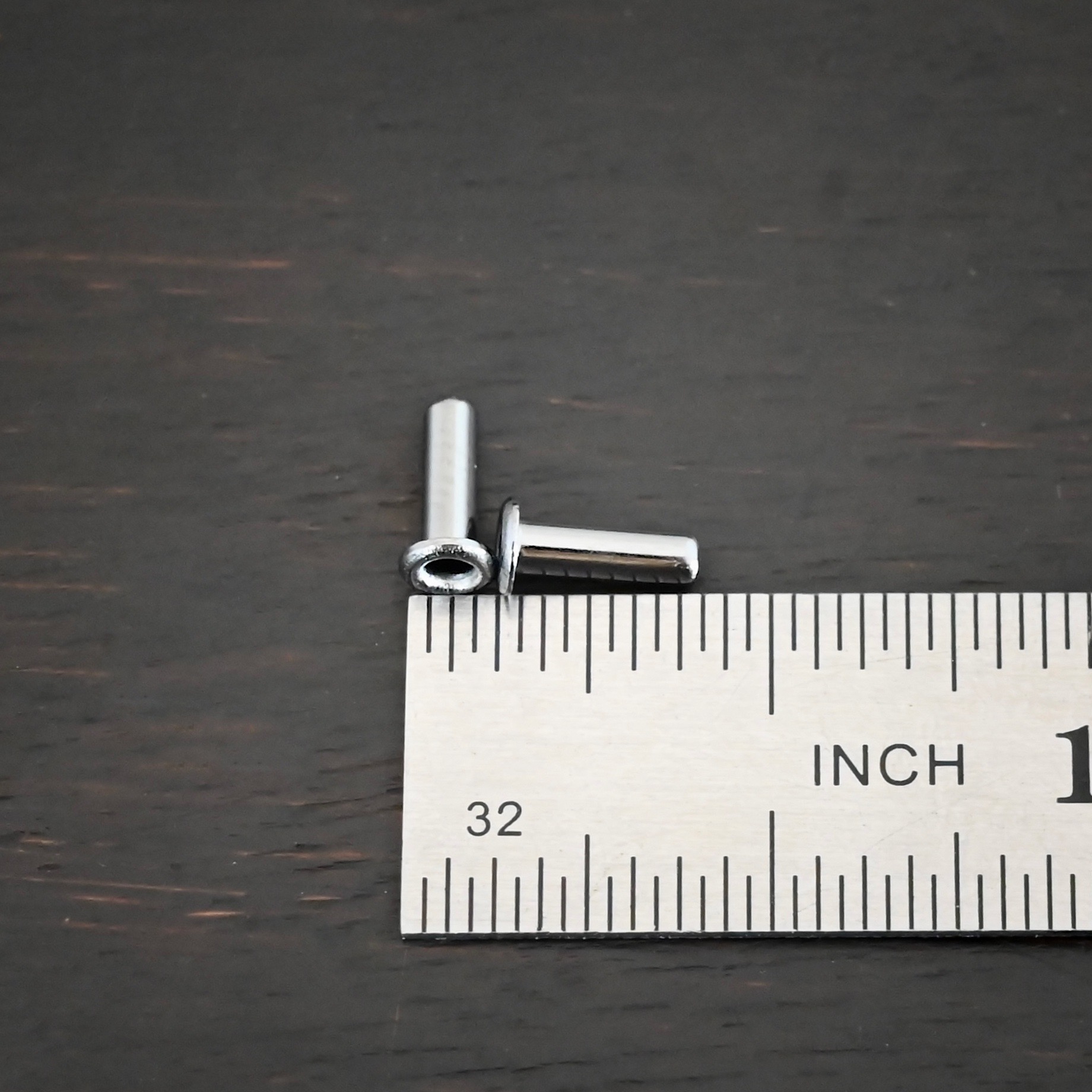 3/32x1/4 plated gunmetal eyelets shown by ruler