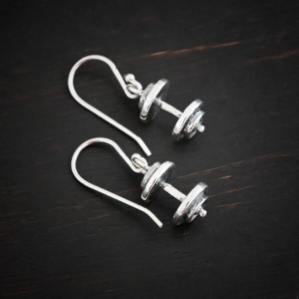 Silver barbell charm earrings shown on dark background
