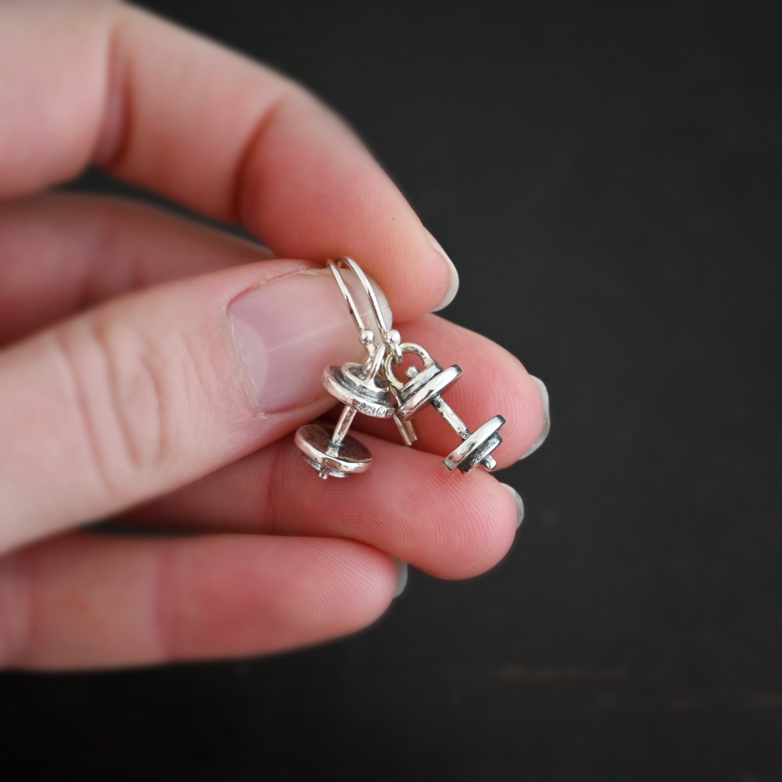 Silver barbell charm earrings shown in hand