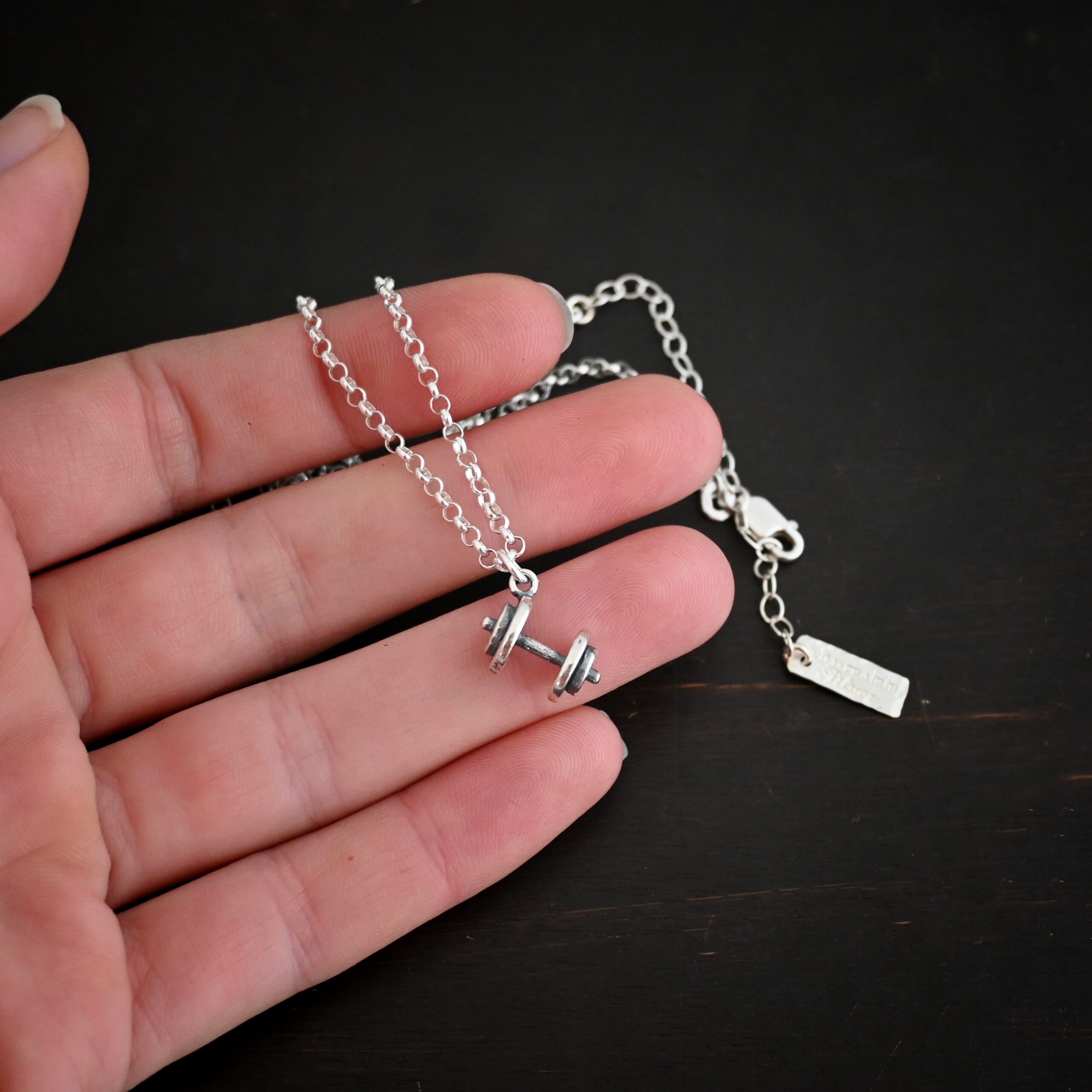 Silver barbell charm necklace shown in hand