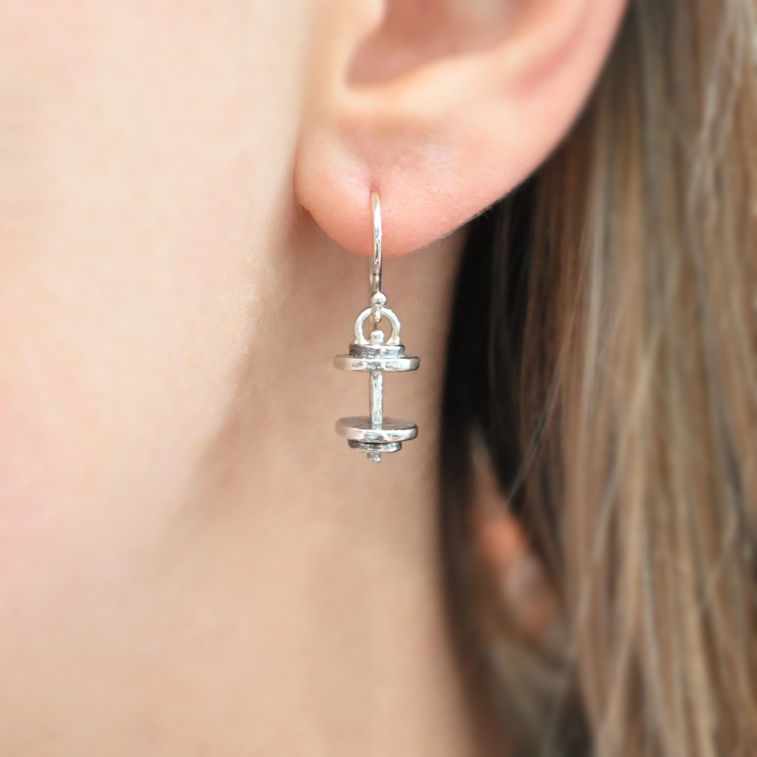 Silver barbell charm earrings shown in ear
