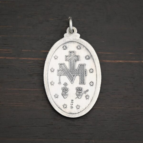 Back side of Silver Mary Medallion Oval Charm 20x29mm on dark background