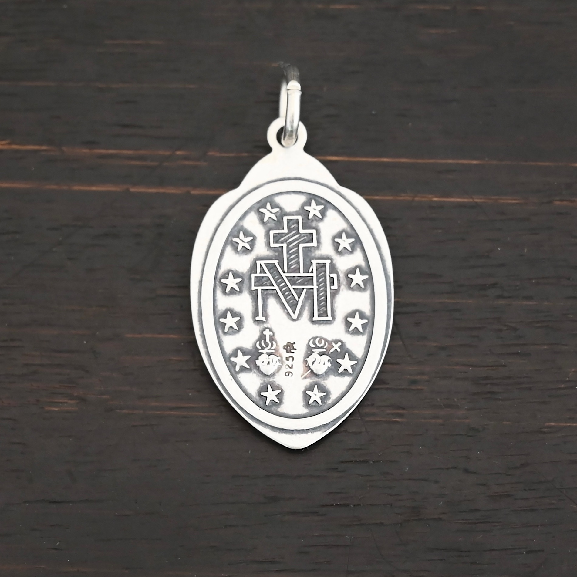 Silver back side of Mary Medallion 26x15mm charm shown on dark background