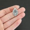Silver back side of Mary Medallion 26x15mm charm shown in hand