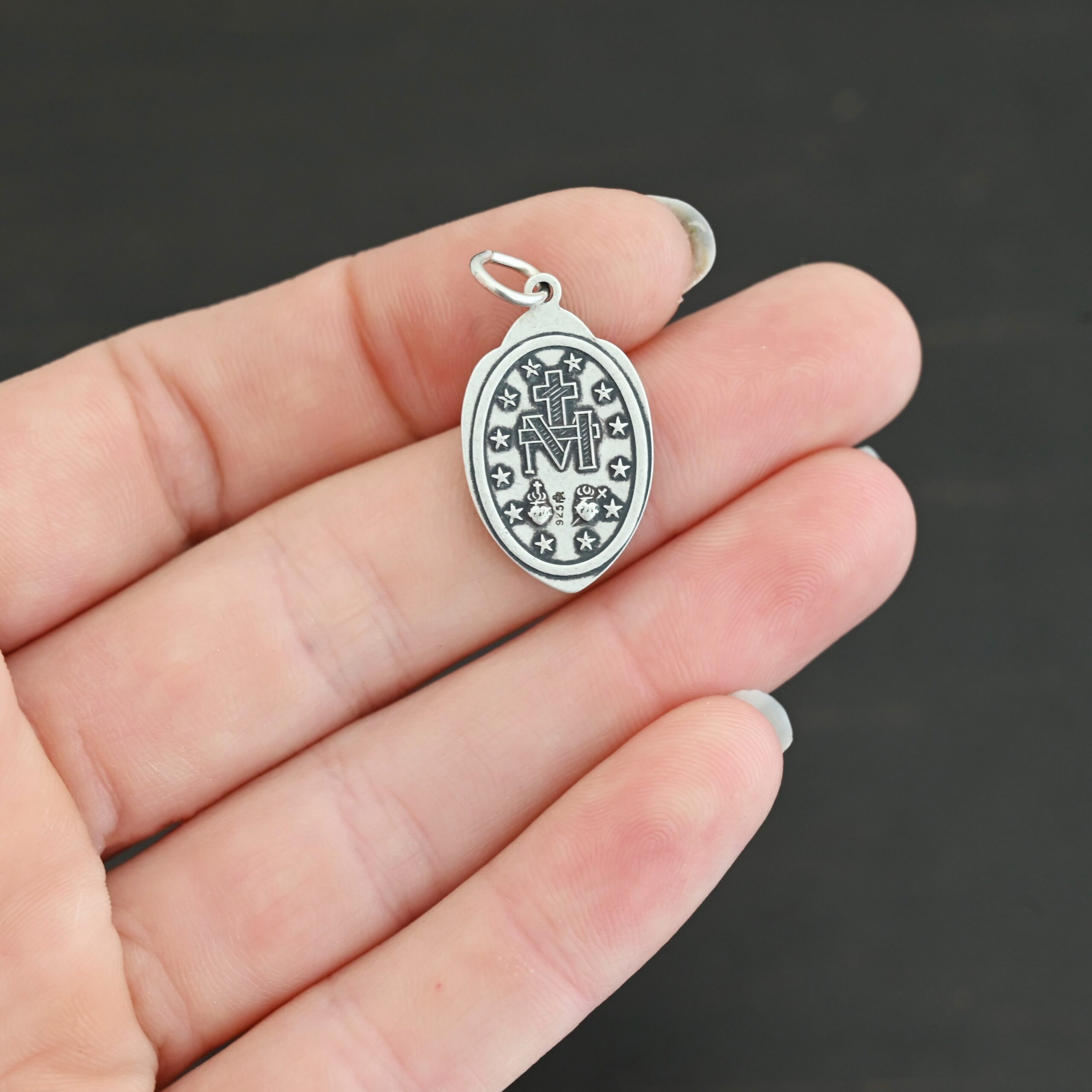 Silver back side of Mary Medallion 26x15mm charm shown in hand