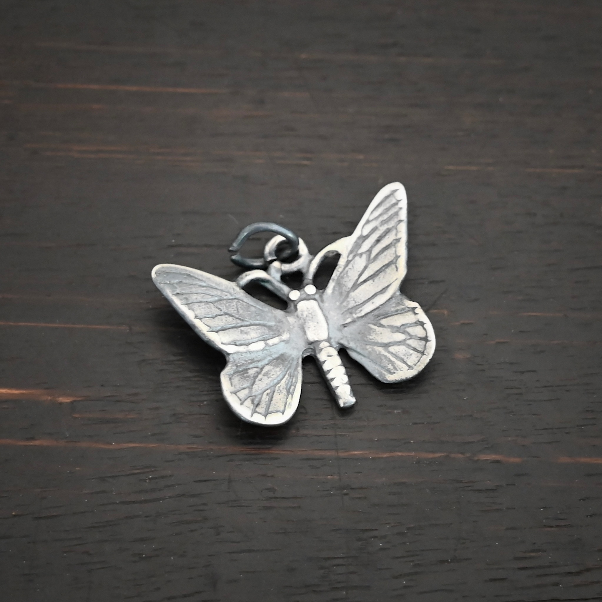 Silver Butterfly Charm oxidized shown on dark background