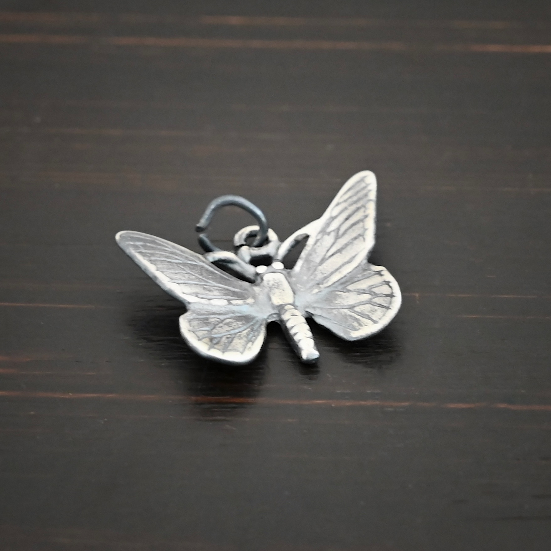 Silver Butterfly Charm oxidized shown on dark background