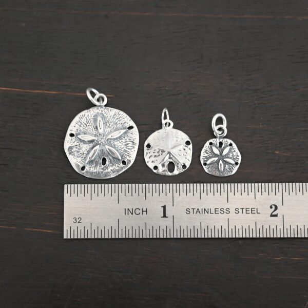 Silver Sand Dollar Charms shown by ruler