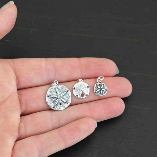 Silver Sand Dollar Charms shown in hand