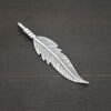 Silver shiny double sided feather charm shown on dark background