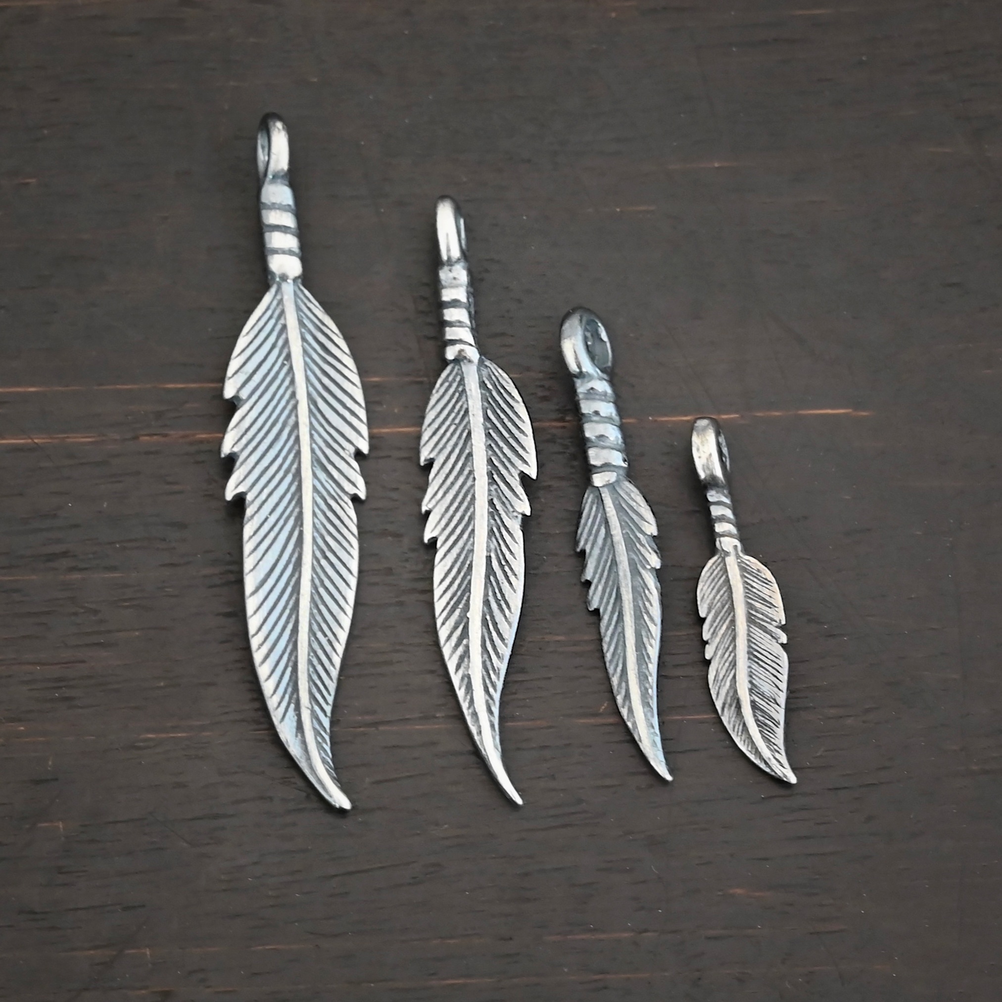 Silver oxidized double sided feather charms all sizes shown on dark background
