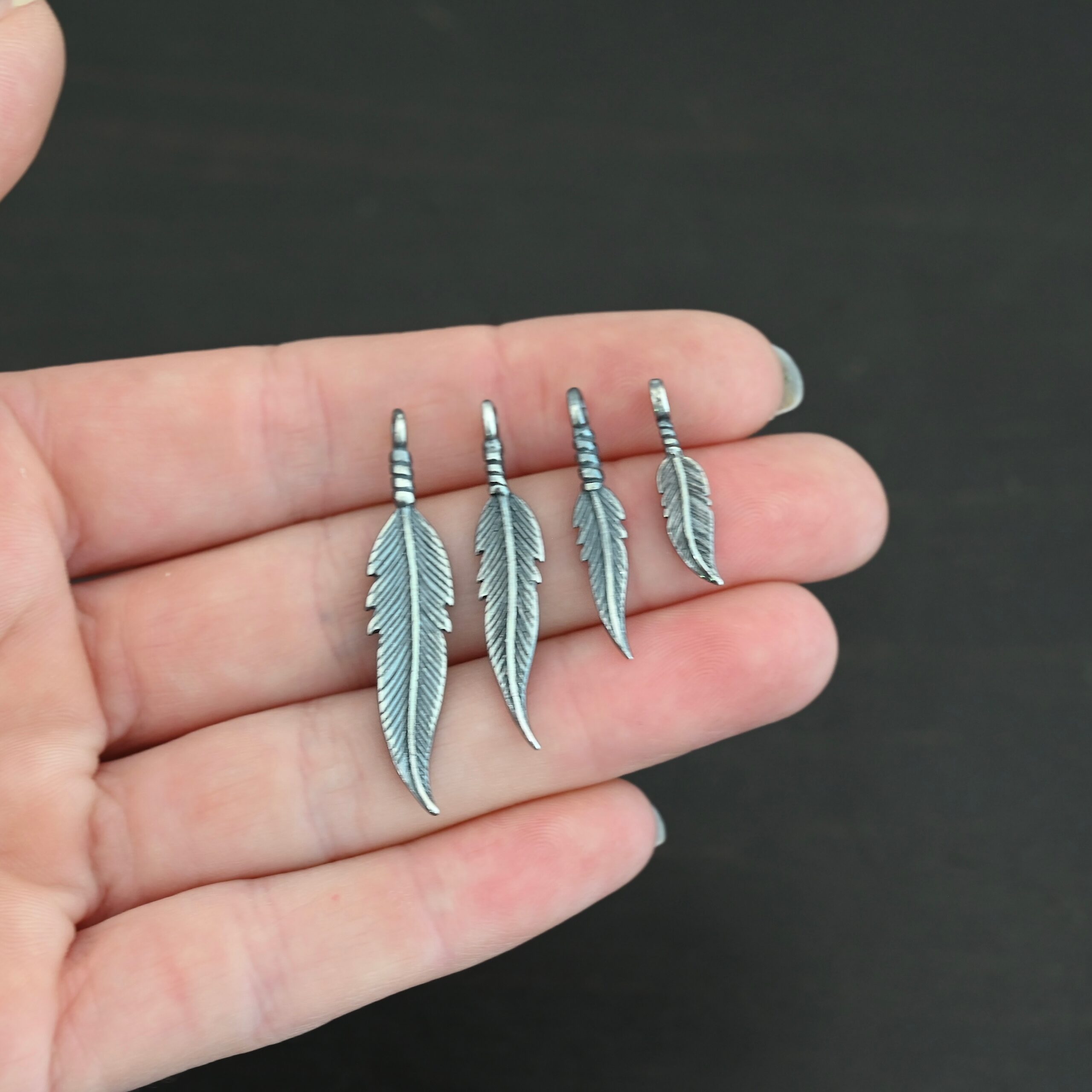 Silver oxidized double sided feather charms all sizes shown in hand