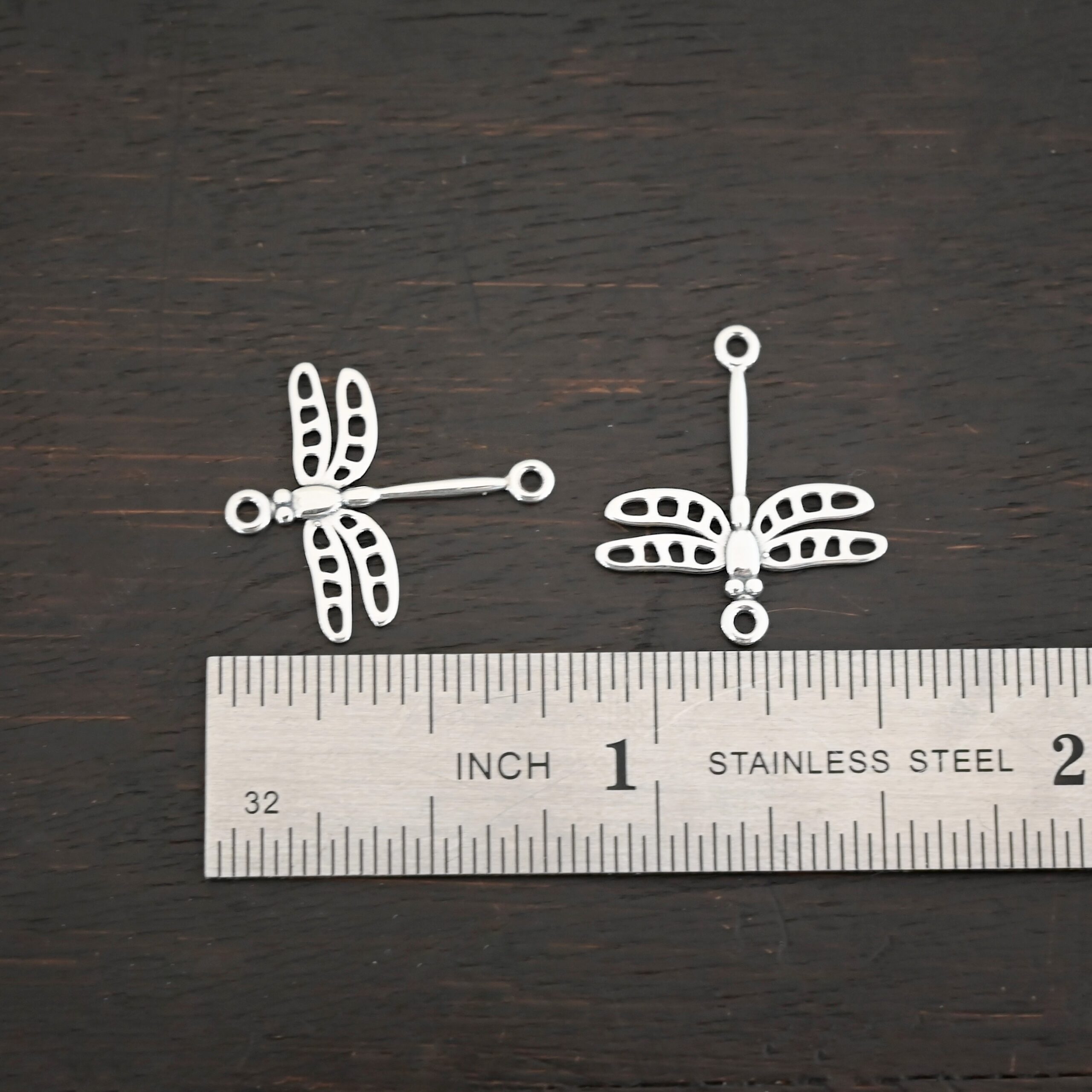 Silver shiny dragonfly charms shown by ruler
