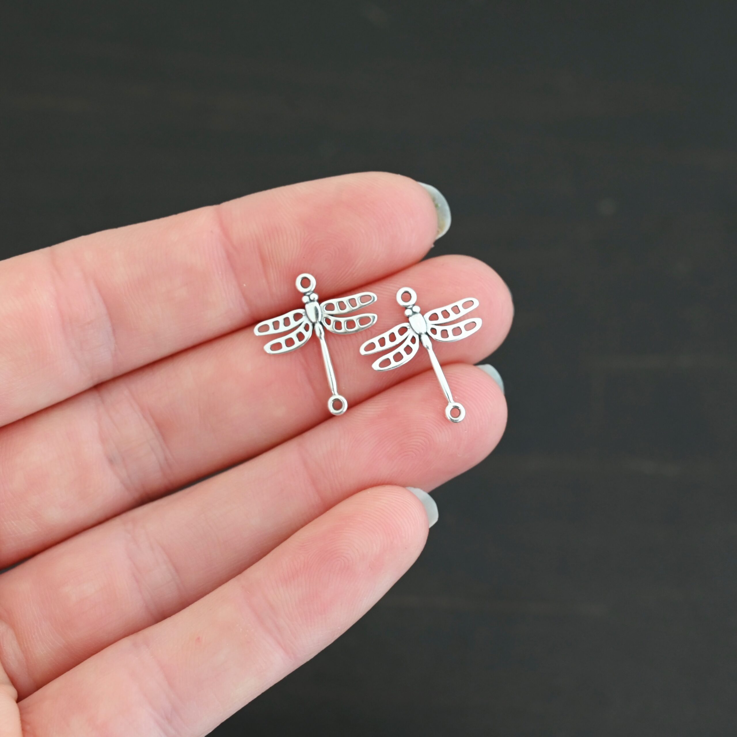 Silver shiny dragonfly charms shown in hand