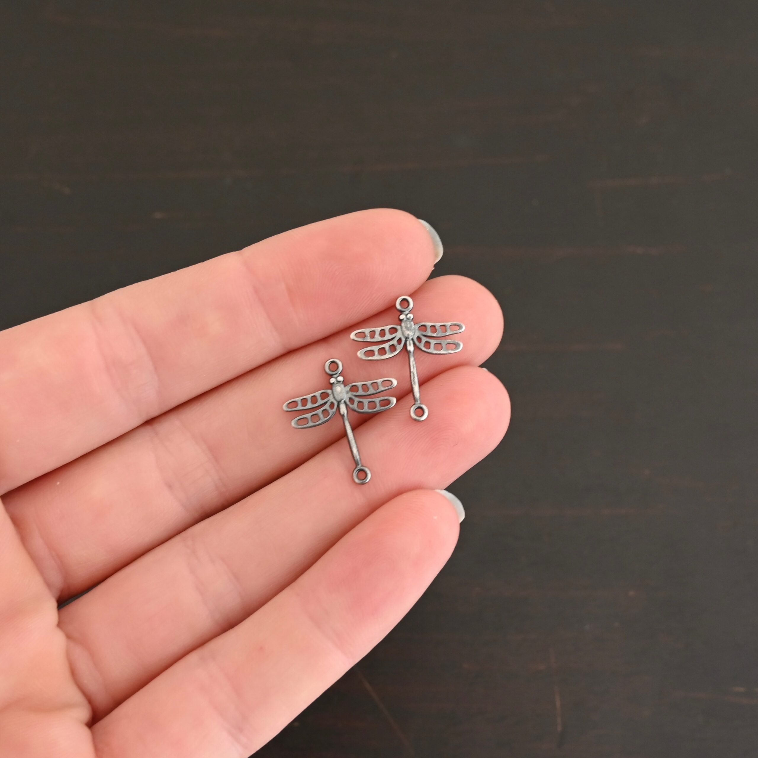Silver oxidized dragonfly charms shown in hand