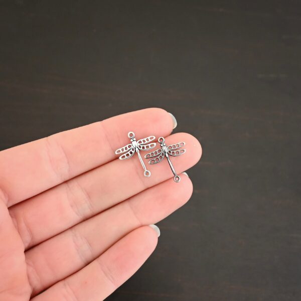 Silver shiny & oxidized dragonfly charms shown on hand