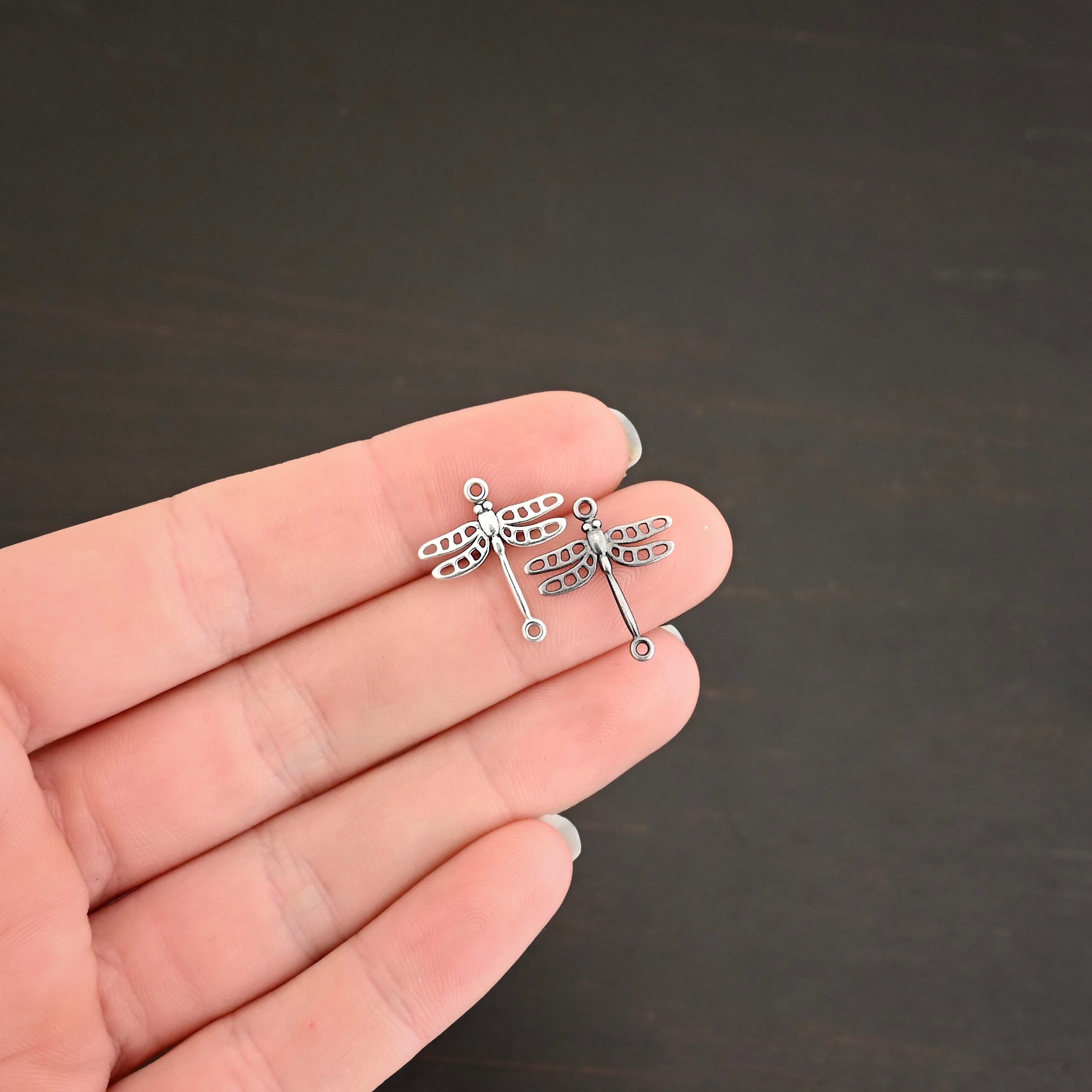 Silver shiny & oxidized dragonfly charms shown on hand