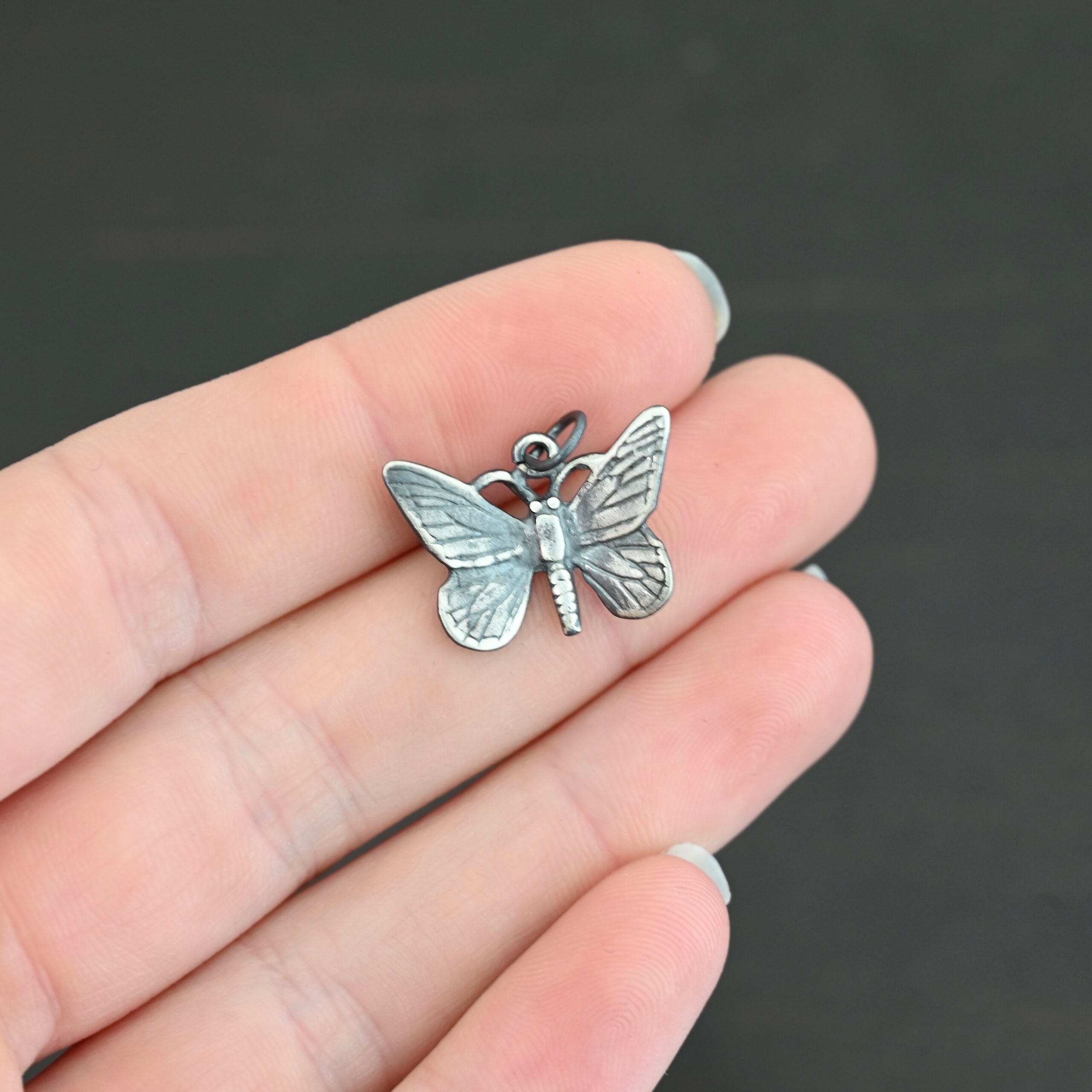 Silver oxidized butterfly charm shown in hand
