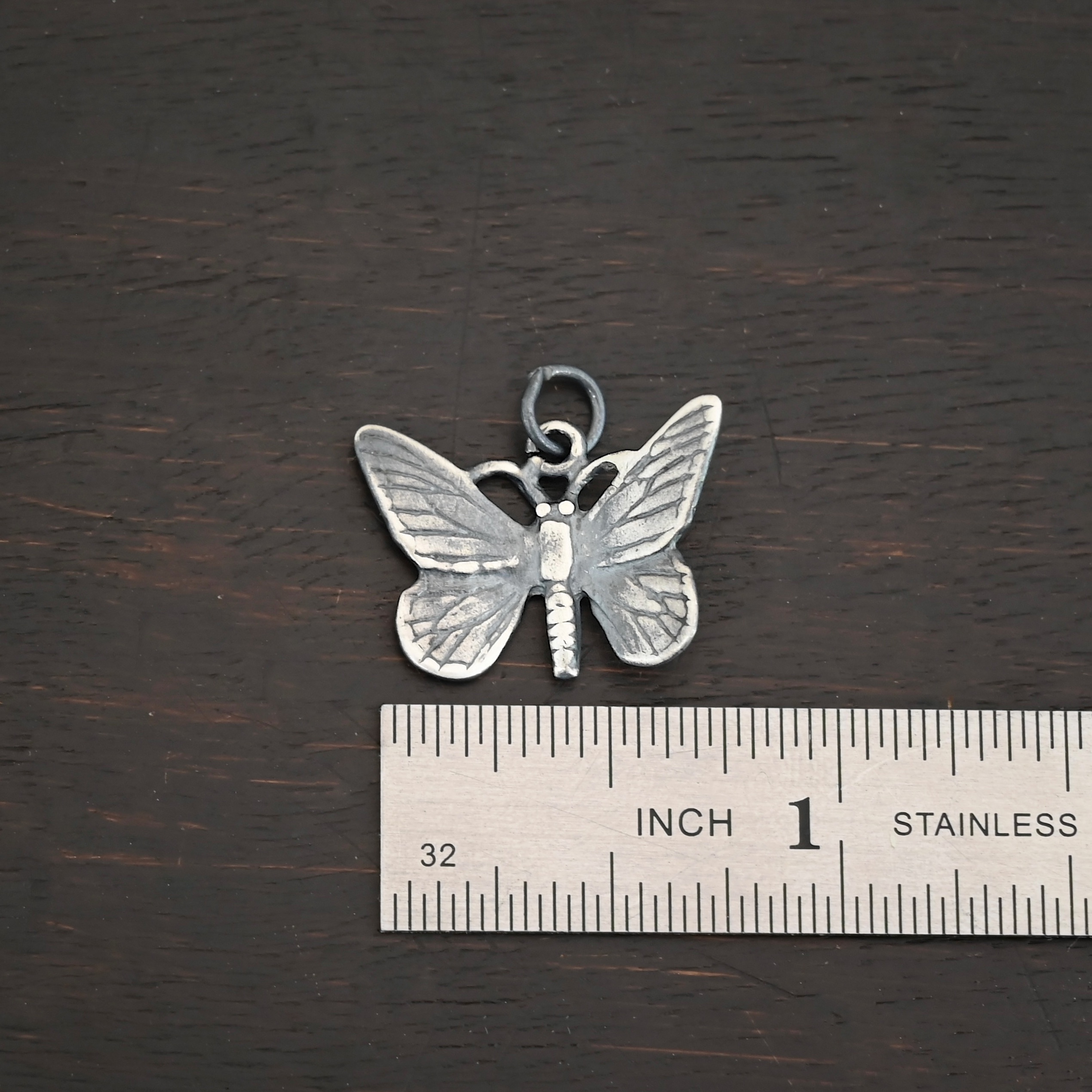 Silver oxidized butterfly charm shown by ruler