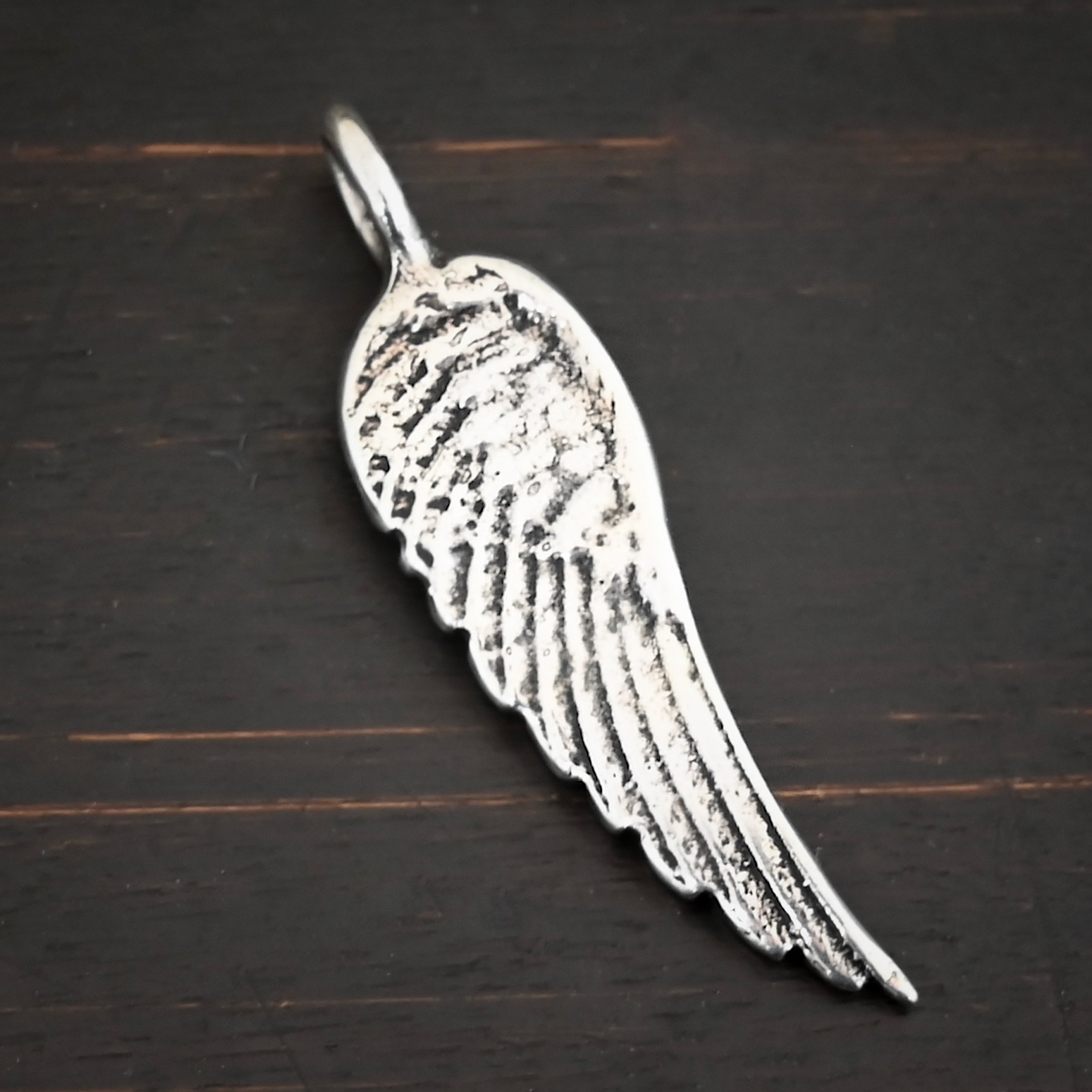 Silver Angel Wing charm shiny charm shown on dark background