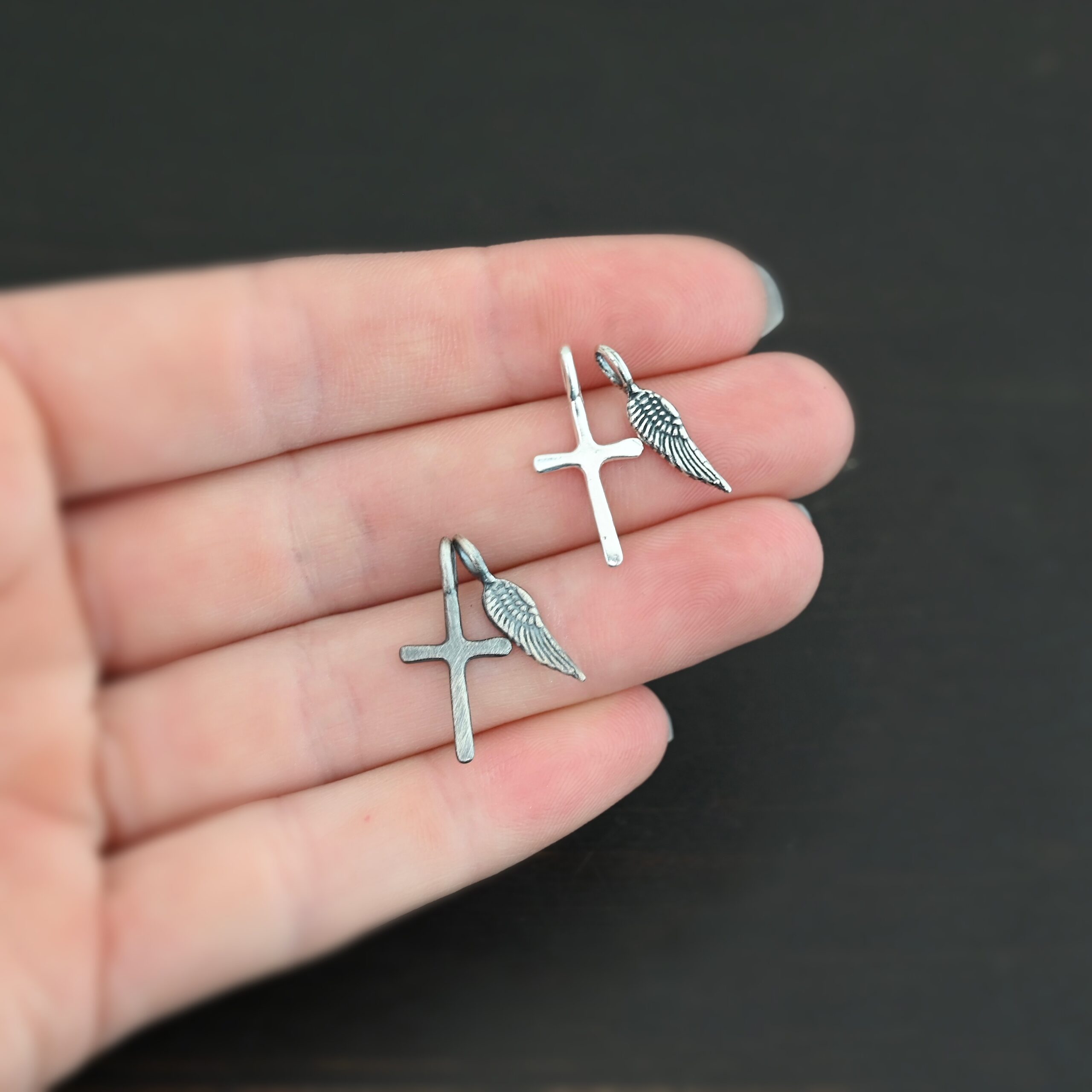 Silver small cross & angel wing charm shiny & oxidized shown in hand
