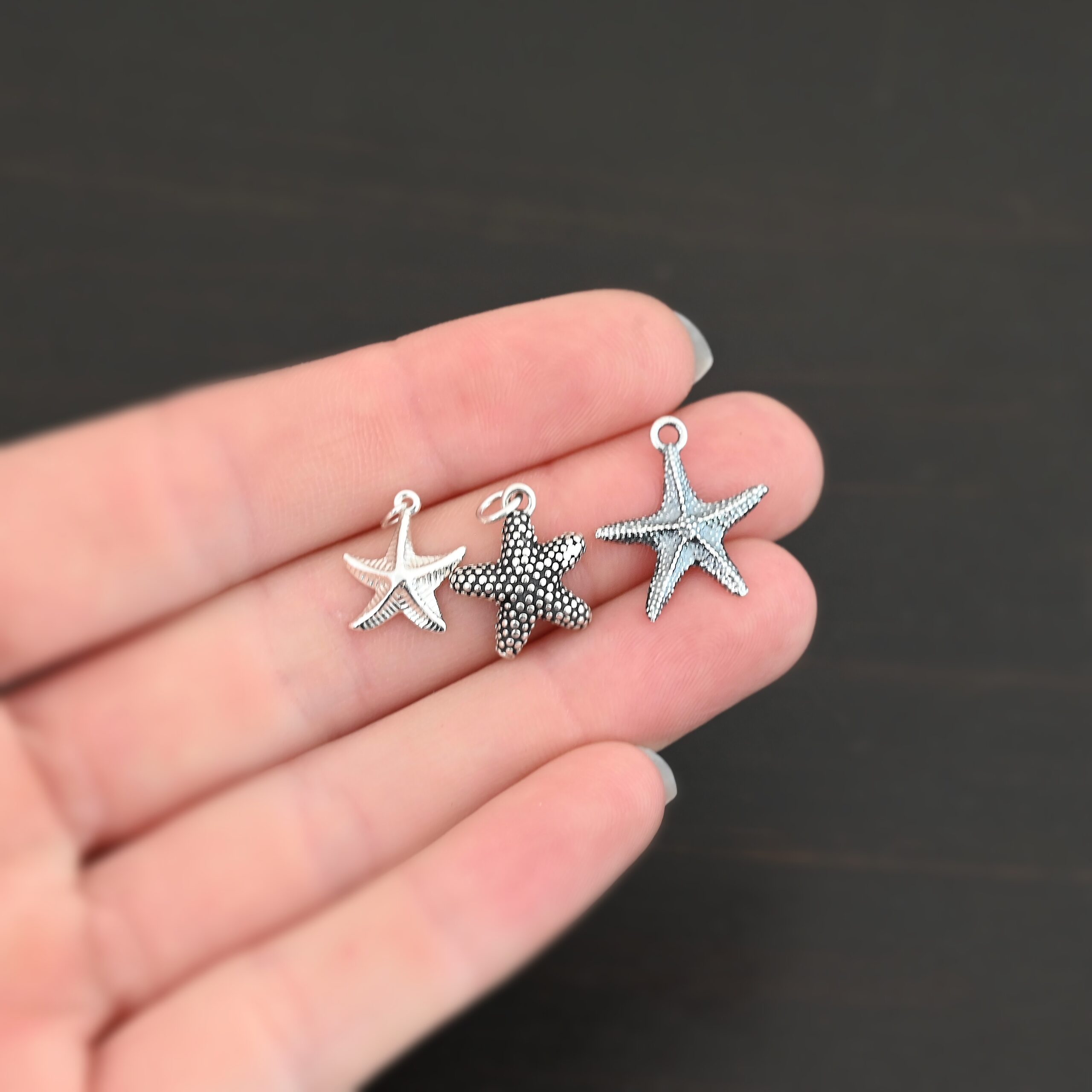 Silver star fish charms shown in hand