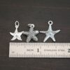 Silver star fish charms shown by ruler