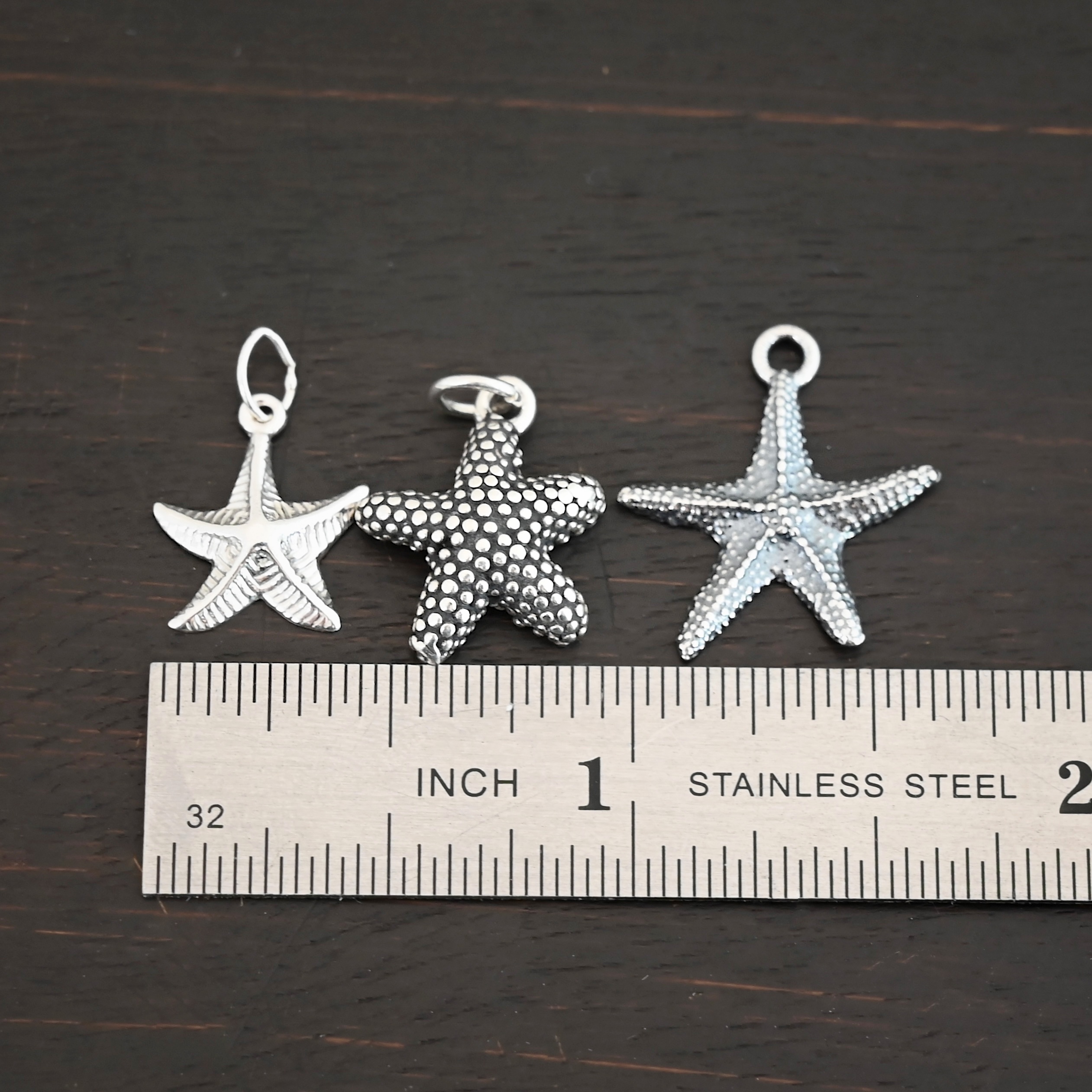 Silver star fish charms shown by ruler