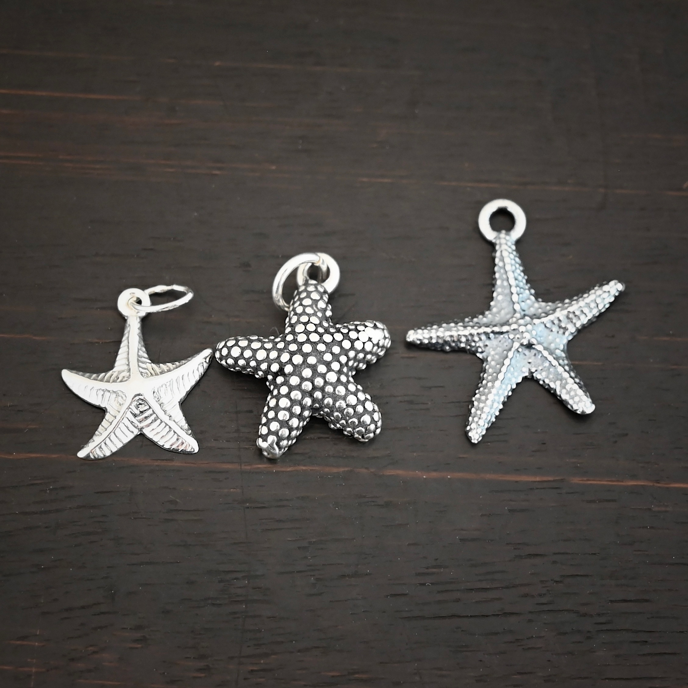 Silver star fish charms shown on dark background