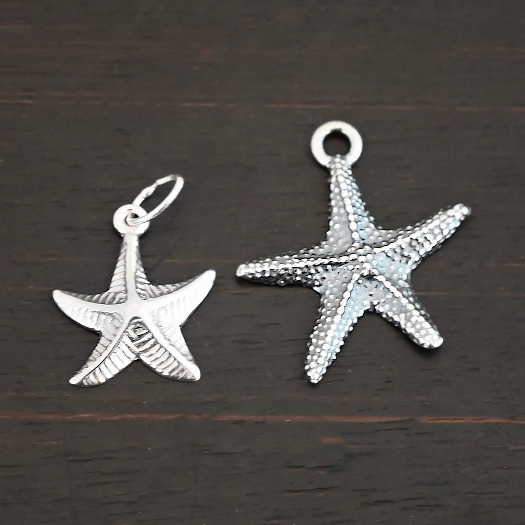 Silver star fish charms shown on dark background